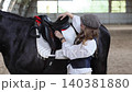 Woman adjusting horse saddle in indoor arena 140381880