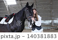 Young woman bonding with black horse in stable 140381883