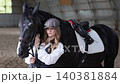 Young woman bonding with black horse in stable 140381884