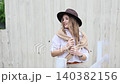 Stylish woman wearing fedora and white shirt by fence 140382156