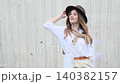 Woman holding hat on windy day with flying hair 140382157