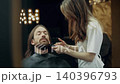 Female Barber Trimming Client Beard in Salon 140396793