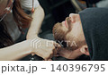 Female Barber Trimming Client Beard in Salon 140396795