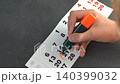 Hand Marking an Important Date on a Calendar Page with an Orange Highlighter 140399032