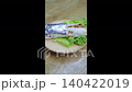 Savory meat wrap or kebab partially wrapped in foil, served on a fresh green lettuce leaf on a round wooden plate. High angle close-up of appetizing street food on a rustic wooden table background. 140422019