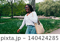 Smiling woman stands in park with green grass and trees on a sunny day in summer 140424285