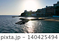 4K drone footage of Nishiura Palm Beach on the Nishiura Peninsula in Gamagori City, Aichi Prefecture, capturing the reflection of the sunset on the water's surface from a low altitude. 140425494