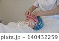 Professional beautician performing facial massage with pink towel 140432259