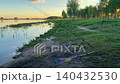Fishing rods on a quiet lake shore at sunset, relaxing in the fresh air and a summer natural landscape with birch trees. 140432530