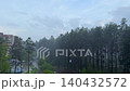 Heavy rainfall over a pine forest near city buildings, a backdrop for a landscape during a storm and urban weather. 140432572