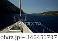 Bowsprit and hatch in the deck of a sailing yacht sailing in a narrow strait between rocky shores 140451737