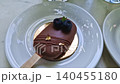 Two elegant chocolate popsicle cakes sit on the table near tall glasses of refreshing mint mojito lemonade with ice. The dessert is topped with peanuts, blueberries and gold foil 140455180