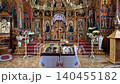 The inside view of Varzaresti Monastery with sacred icons resting on a white embroidered stand, revealing a grand golden iconostasis, a massive ornate chandelier, and breathtaking Biblical frescoes 140455182