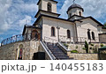 Outdoor view of Varzaresti Monastery with a cobblestone courtyard and a prominent bell tower with a dark dome topped with Christian crosses under a beautiful sky 140455183