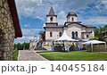 Outdoor view of Varzaresti Monastery with a cobblestone courtyard and a prominent bell tower with a dark dome topped with Christian crosses under a beautiful sky 140455184
