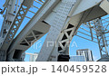 A low angle perspective shows the massive scale of gray steel girders and diagonal supports on an industrial bridge. The intricate pattern of rivets and beams creates a strong architectural presence 140459528