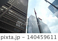 Tall skyscrapers rise above with an American flag waving between modern buildings in a downtown city. The low angle view emphasizes height, architecture, and national identity in an urban environment. 140459611