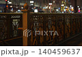 Chicago street scene at night with decorative metal bridge railing and blurred city lights in the background. Urban infrastructure and traffic create a warm illuminated evening atmosphere. 140459637