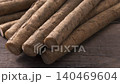 A close-up of fresh burdock roots arranged in bundles on a wooden table. 140469604