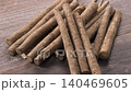 A close-up of fresh burdock roots arranged in bundles on a wooden table. 140469605