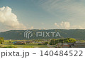 A Japanese rural landscape with the setting sun and mountain ranges stretching out before you. 140484522