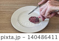 steel fork and knife screeching and scraping when cutting sausage on ceramic plate 140486411