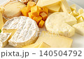 A platter of several types of cheese, including Camembert, arranged on a white plate. 140504792