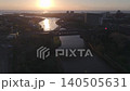 Wide aerial drone shot tracking slowly toward the silhouetted Wearmouth Bridge and Monkwearmouth Railway Bridge at sunrise, featuring a Tyne and Wear Metro train crossing the River Wear. 140505631