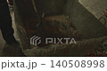 Construction worker manually mixing wet cement and sand with water in a large metal container using a shovel, preparing the mortar for laying concrete floor or plastering a wall 140508998