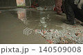 Professional construction worker pouring fresh wet concrete mix onto a prepared surface and then carefully leveling the screed using a long metal straightedge for a smooth finish 140509008