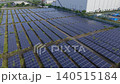 [Aerial view] Panoramic view of a mega solar power plant adjacent to a huge warehouse and factory (Image material for ESG investment, SDGs, and corporate activities) 140515184