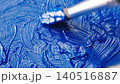 An artist mixing the blue oil paint on a transparent glass palette with round brush. Relaxing close 140516887