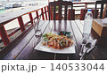 Thai food - pad thai noodles with vegetables on plate on the table in rustic restaurant. Thai food restaurant view with water bottle and tissue box on wooden table ideal for travel and vacation dining 140533044