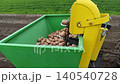 Mechanical potato planter machine working on farm field. Green and yellow agricultural equipment planting potato tubers in the soil. Modern farming process and agricultural industry 140540728
