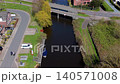 Aerial view of a scenic water canal with a bridge, small boat dock, and traditional houses in a cozy Dutch village countryside, Netherlands during spring season. 140571008