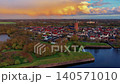 Aerial view of the historic Dutch fortified town Naarden with red roofs, ancient church tower, and green star fort ramparts under a dramatic golden sunset sky, Netherlands. 140571010