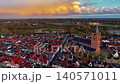 Aerial close-up view of the historic church tower, red roofs, and traditional streets in the fortified town of Naarden under a dramatic golden sunset sky, Netherlands. 140571011