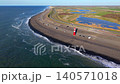 Aerial panoramic view of the red and white lighthouse on Westkapelle sea dike, stone breakwater coast, parked camper vans, and scenic polder landscapes in Zeeland, Netherlands during spring. 140571018