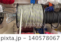 Close-up video of steel wire rope wound on blue spool in hardware store. The rope is pulled and the spool rotates. 140578067