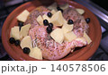 Raw chicken legs seasoned with spices, potatoes, and black olives cooking in a traditional terracotta tagine pot on a gas stove, showcasing authentic moroccan cuisine preparation at home 140578506