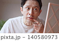 鏡を見ながら口元にできた口唇ヘルペスの症状に悩み、顔をしかめるミドル男性 鏡を見ながら口元にできた口唇ヘルペスの症状に悩み、顔をしかめるミドル男性 140580973