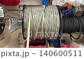 Close-up video of steel wire rope wound on blue spool in hardware store. The rope is pulled and the spool rotates. 140600511