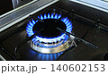 Gas burner igniting on kitchen stove in dark interior, close up of blue natural gas flame appearing on household cooker, domestic energy use, cooking appliance, gas consumption, utility bills, rising 140602153