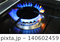 A slow-motion shot of a blue flame igniting on a gas burner on a kitchen stove. A close-up of a household gas stove in a dark room. Energy consumption during cooking, gas consumption, utility bills 140602459