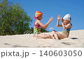 Girls in swimsuits play together on a sandy beach on a hot summer vacation day 140603050