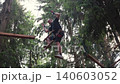 A man climbs a suspension bridge at a height between trees in a rope amusement park. 140603052