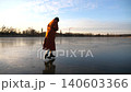 Woman in coat and figure skates sliding on ice on frosty winter day. Girl skating on frozen river or lake. Lady enjoying sport and improves skills in cold weather. Active leisure at wintertime. Slowmo 140603366