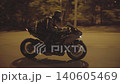 Young motorcyclist riding fast on powerful sport motorbike at evening street. Male biker in protective moto equipment racing on his modern motorcycle at night road. Concept of freedom. Close up 140605469
