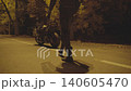 Male biker is going to his modern motorcycle, sitting and starting to ride at night time. Motorcyclist in protective moto equipment is beginning to ride a powerful sport motorbike at evening street 140605470