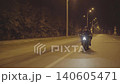 Motorcyclist riding on sport bike with bright headlight at night road. Male racer in protective moto equipment moving on motorcycle at city street. Young man driving motorbike during trip. Front view 140605471